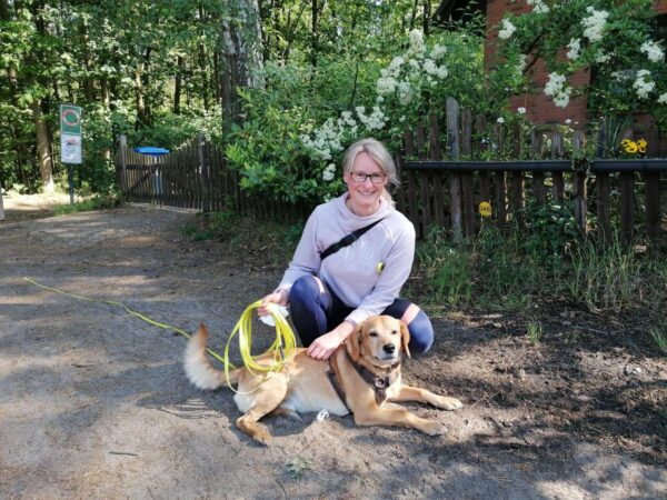 Frau sitzt mit Hund auf einem Gehweg